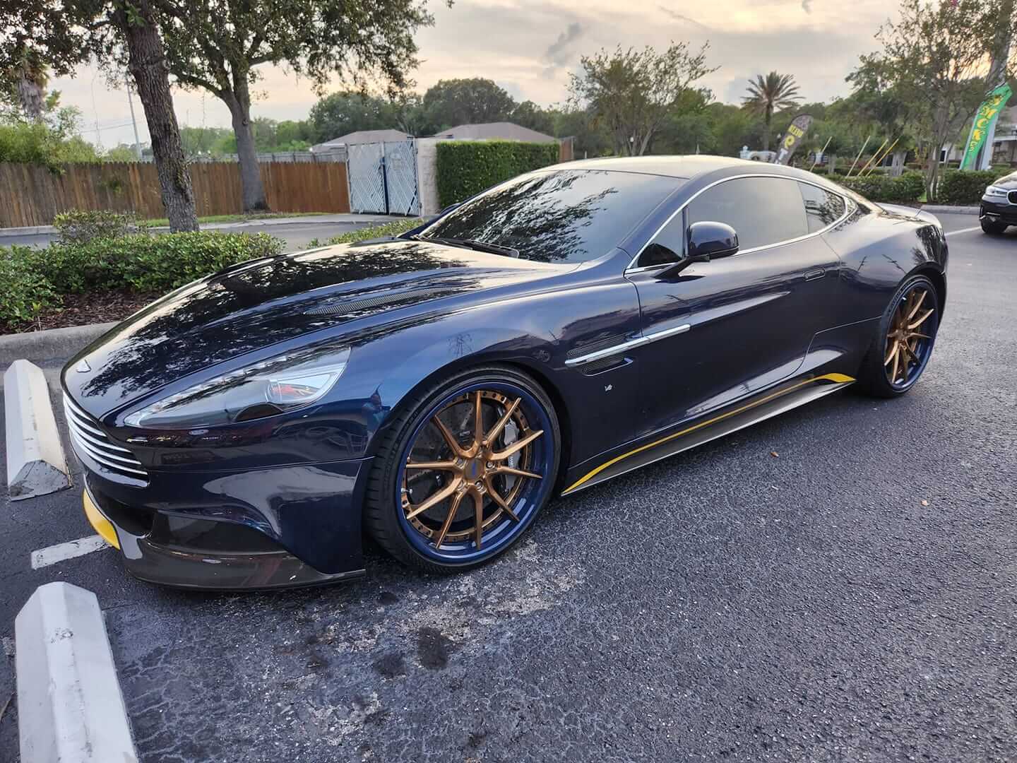 A blue 2016 Aston Martin Vanquish sitting on a custom forged 2-piece wheels with 10 spokes, blue barrel, copper face, 21inch staggered size.
