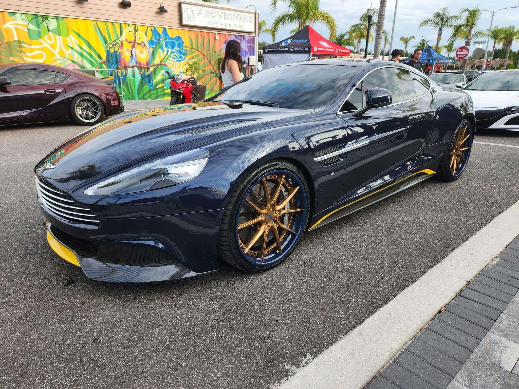 A blue 2016 Aston Martin Vanquish sitting on a custom forged 2-piece wheels with 10 spokes, blue barrel, copper face, 21inch staggered size.