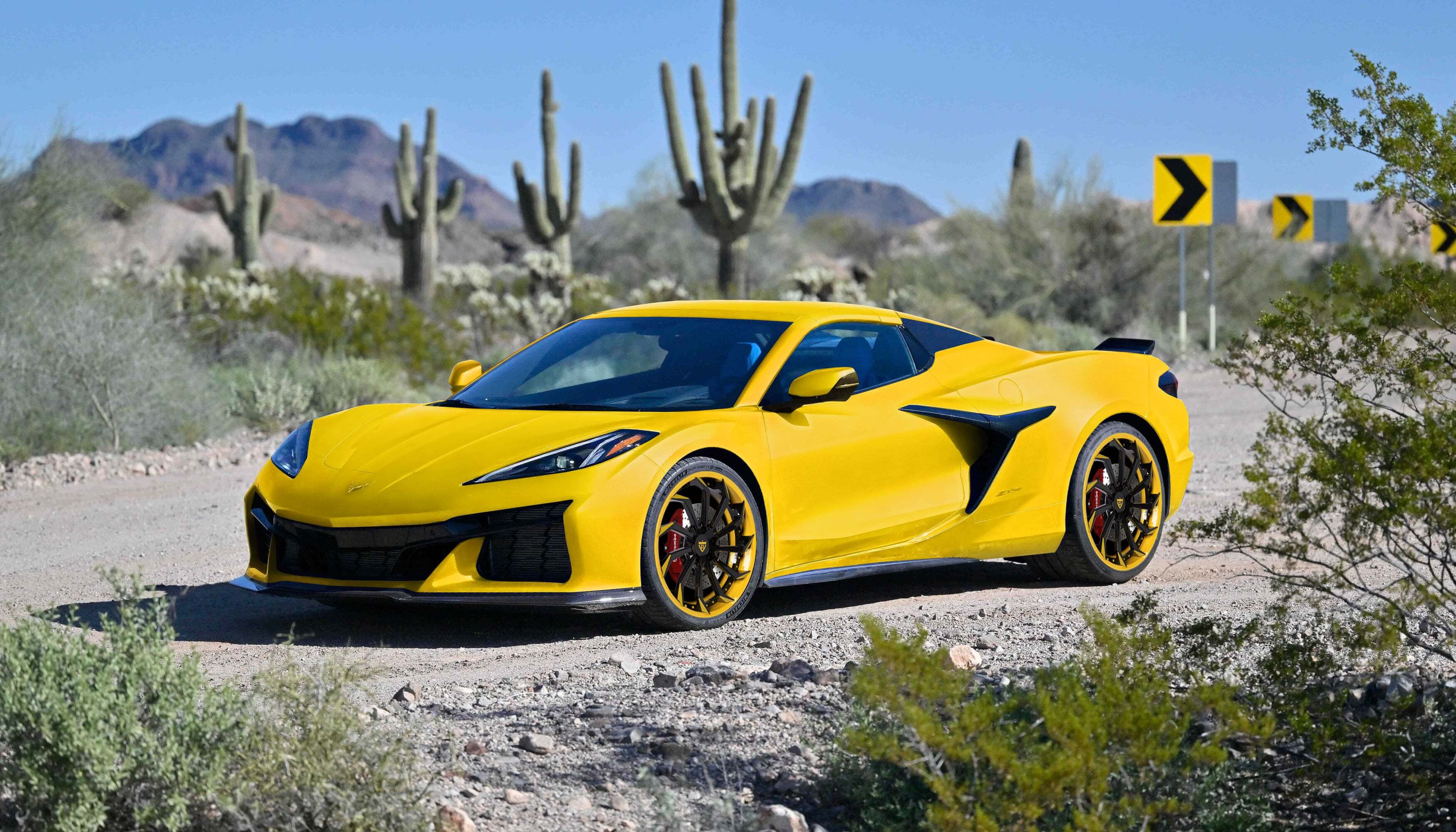 Yellow Corvette with custom forged 2-piece wheels, parked in desert landscape with cactus and mountains in the background