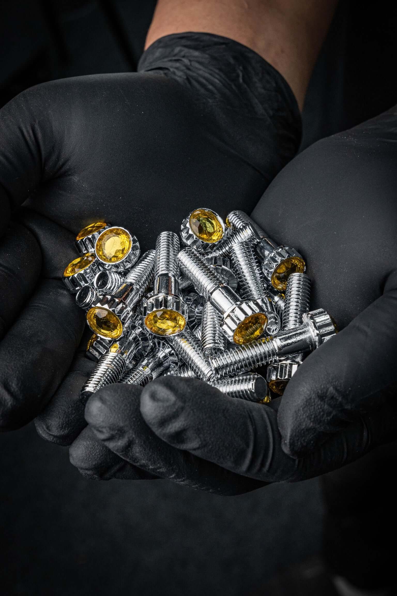 Crystal Shiny Screws for custom-forged rims with yellow rhinestones held in hands wearing black gloves