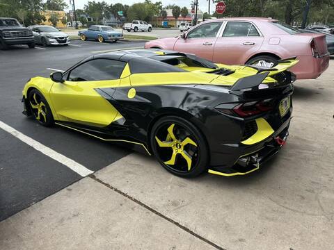 Yellow and black Corvette C8 with aftermarket 5 spoke rims parked on the street showcasing its stunning design.