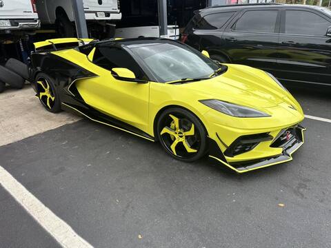 Corvette C8 with yellow and black 5 spoke rims featuring aftermarket wheels parked outside.