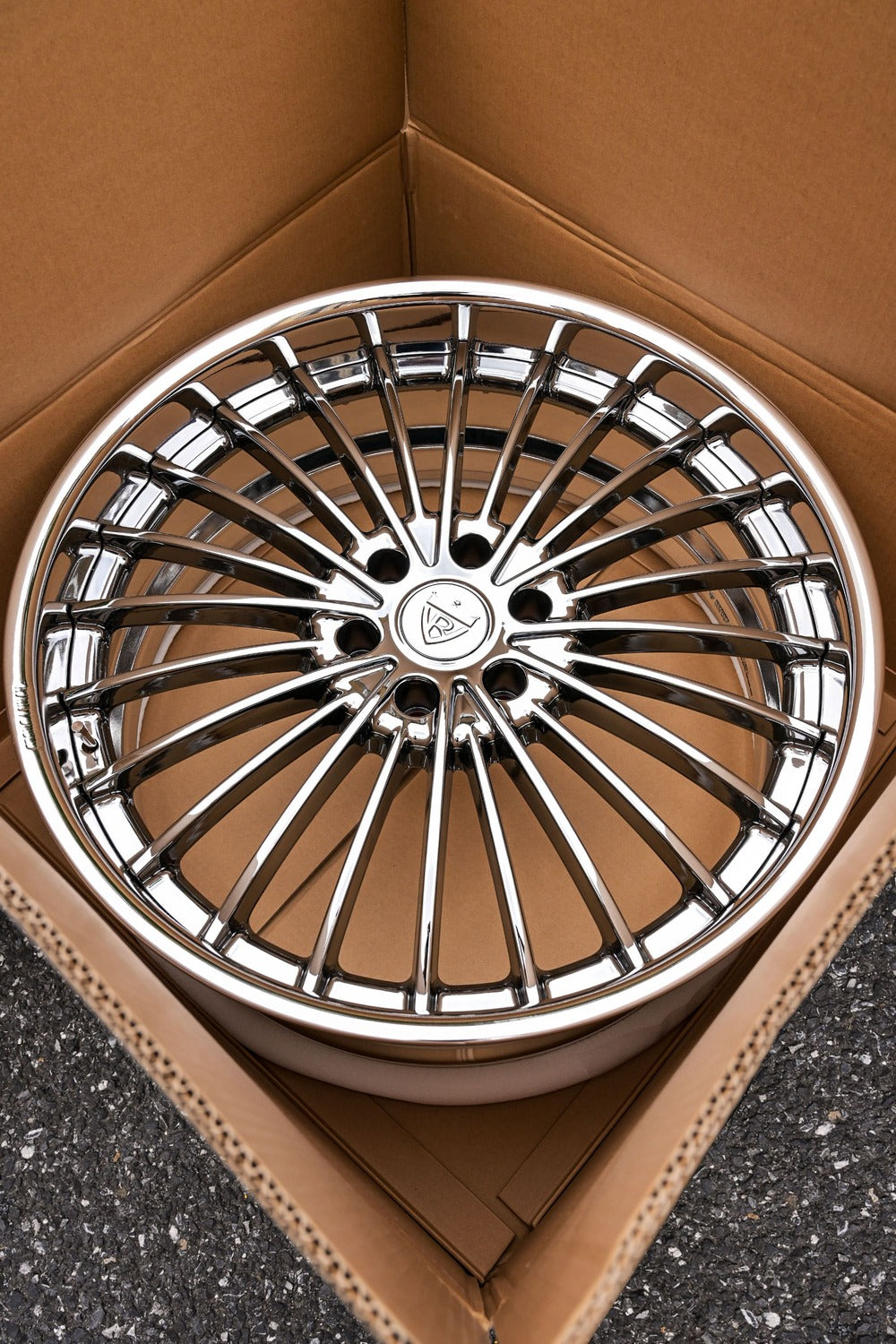 Custom forged black chrome GMC Yukon wheel displayed in a cardboard box, showcasing its intricate design and shine.