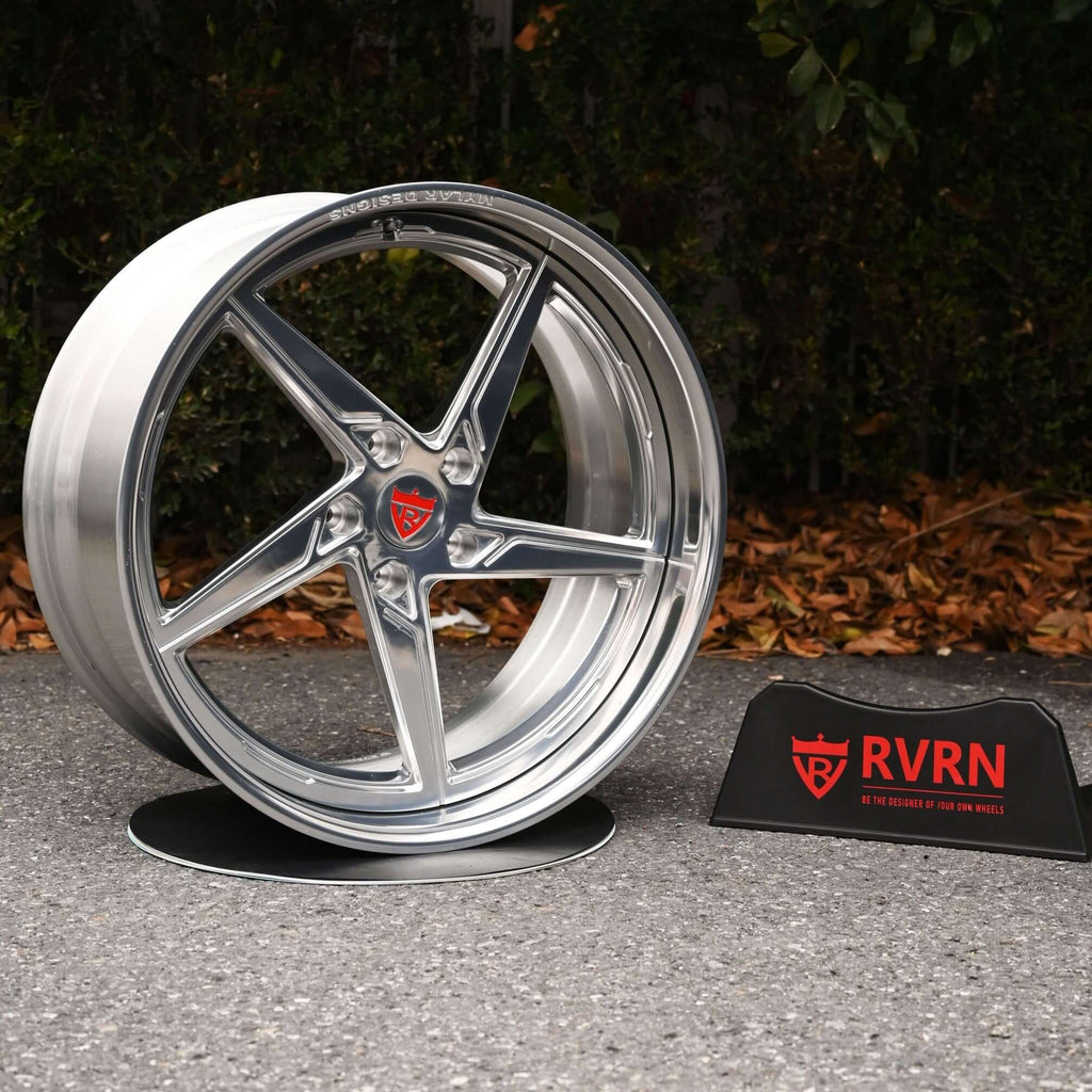 Forged Porsche Cayman 5 spoke deep lip rim displayed on a stand with RVRN logo, showcasing a sleek silver finish.