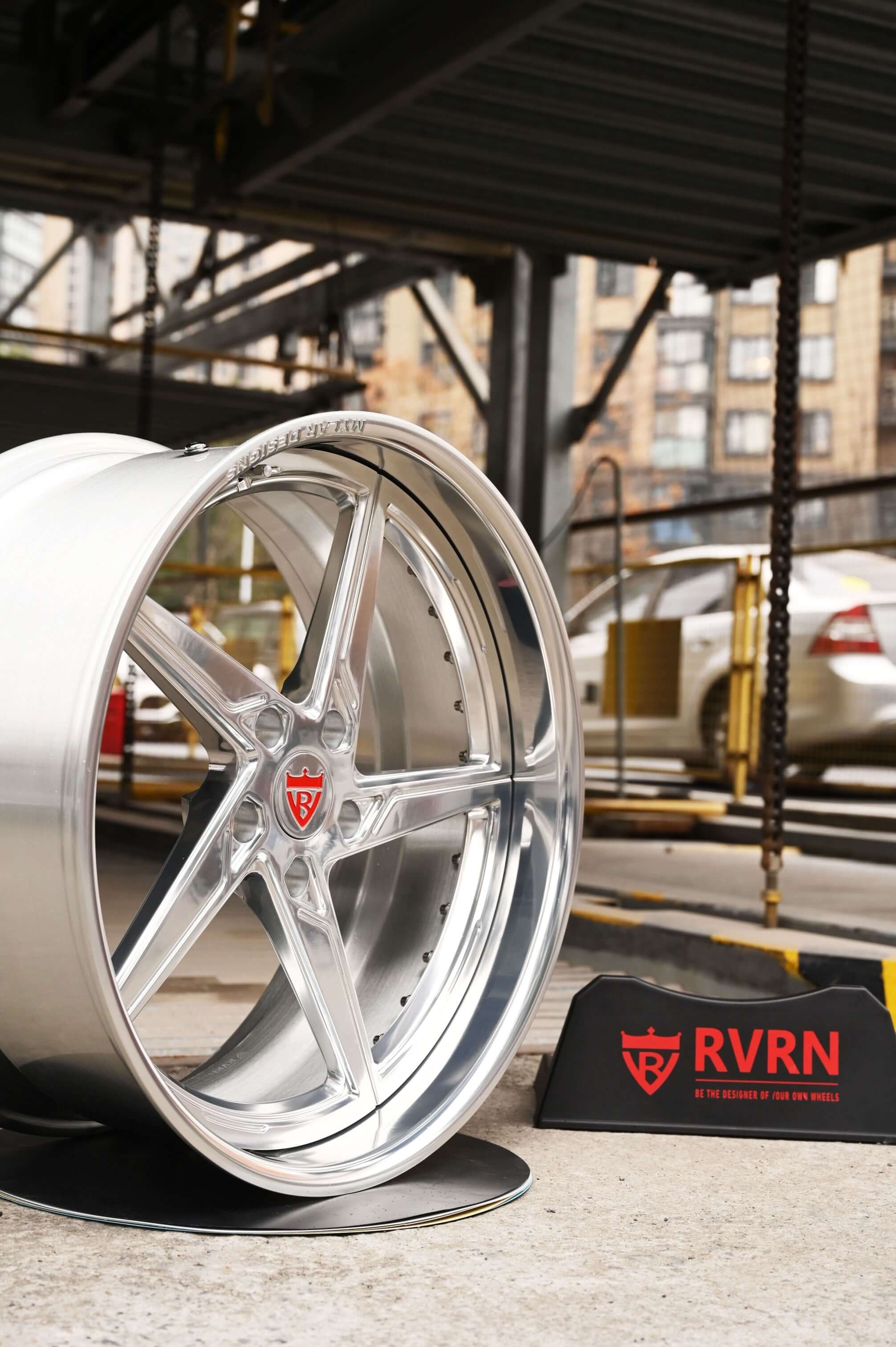 Custom forged Porsche Cayman wheel featuring a 5 spoke deep lip design, displayed prominently with branding in an urban setting.