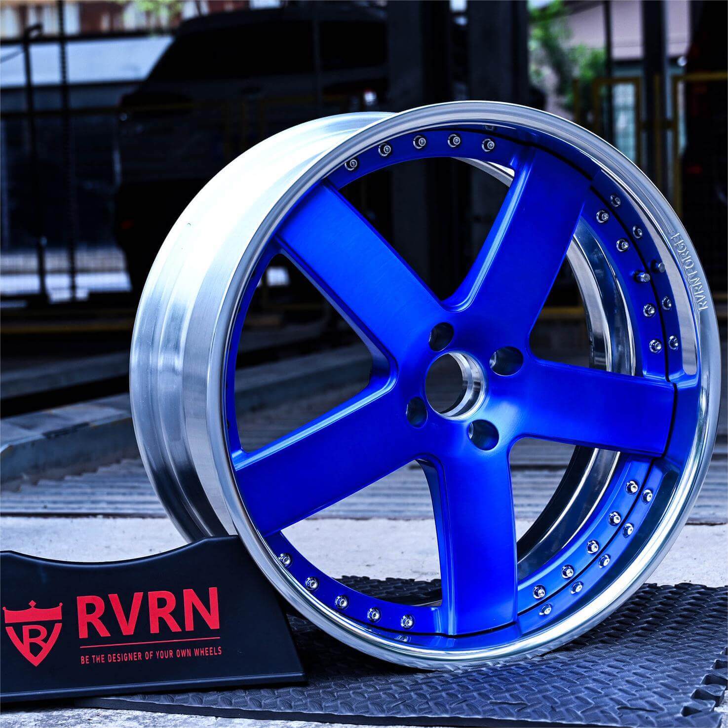 Custom blue 2-piece forged 5-spoke chrome wheel RV-DF93 displayed with RVRN logo in an automotive garage.