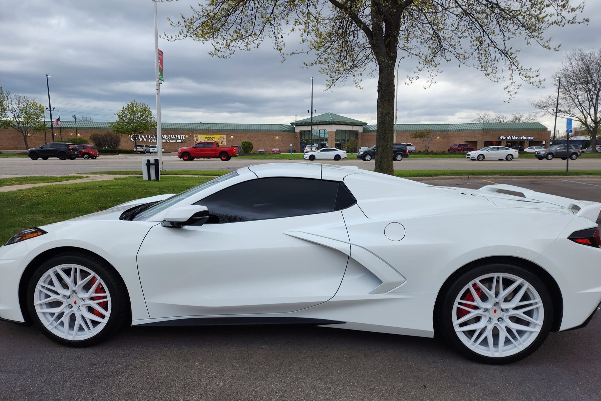 White Corvette C8 showcasing custom aftermarket wheels and rims at a car show, featuring eye-catching design and detailing.