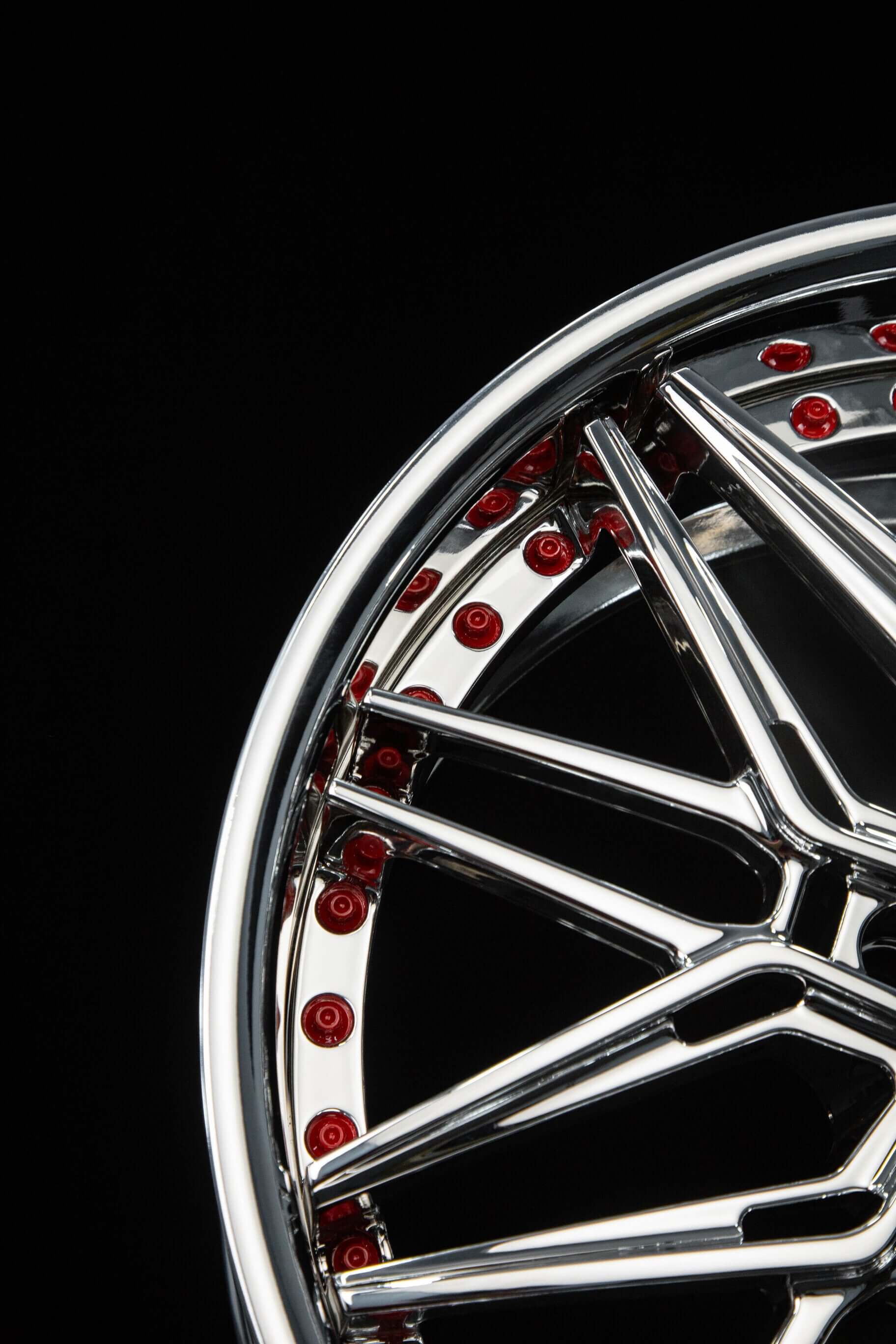 Close-up of chrome C5 Corvette aftermarket wheel featuring a unique design and red accents on a black background.