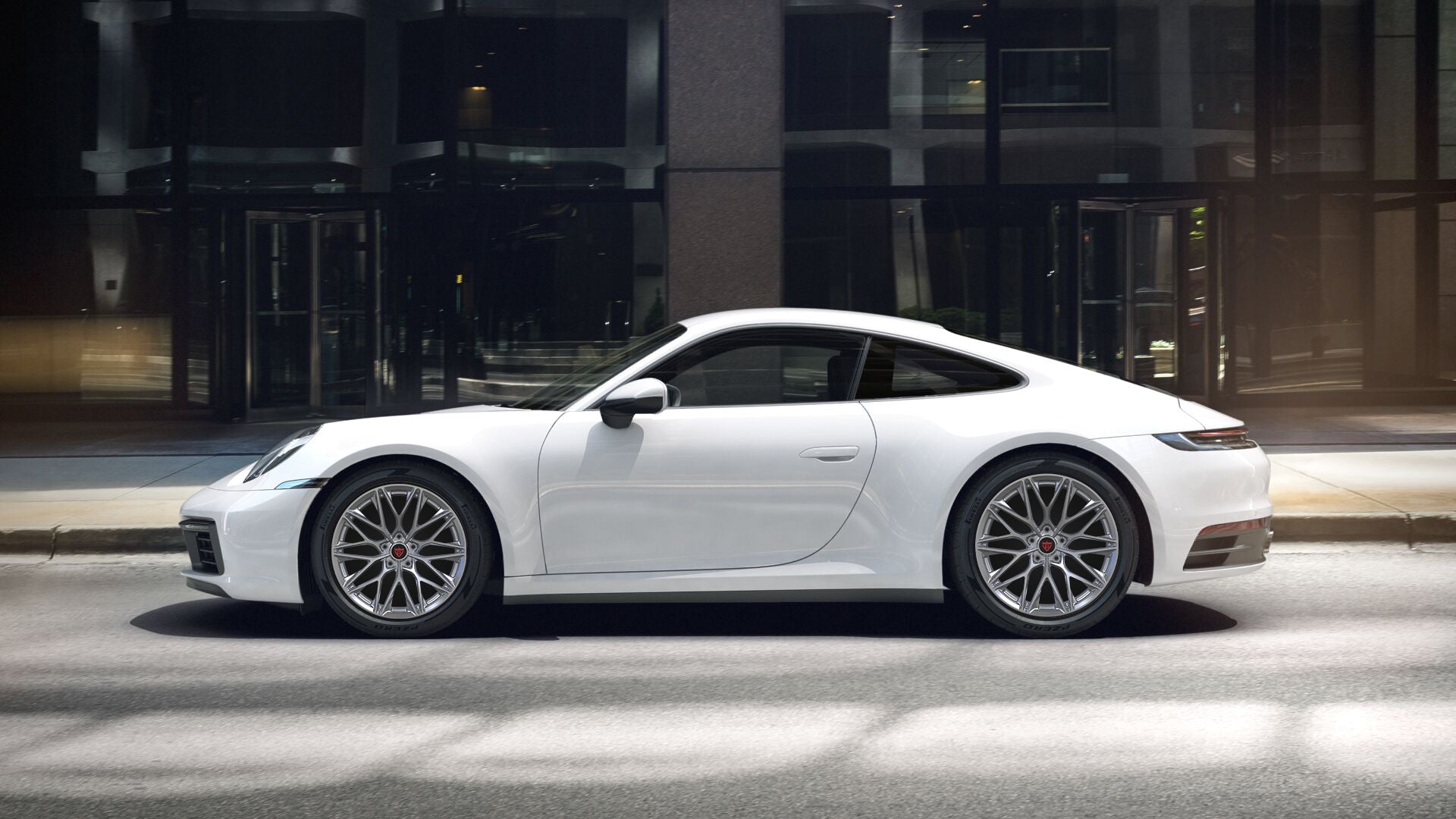 White Porsche 911 with custom forged monoblock wheels parked in urban environment, highlighting style and performance.