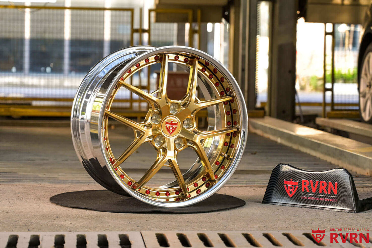 2000 Corvette C5 Custom Polished Frozen Gold Forged Wheels: RV-DR08 displayed on a stand in an industrial setting.