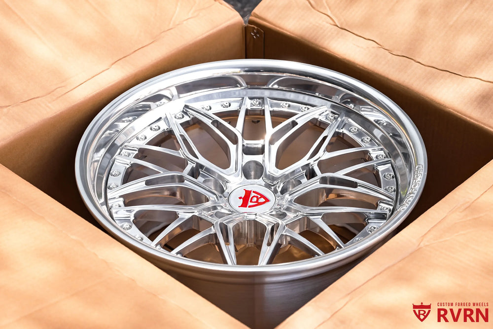 1970 Chevy Nova RV-T081 2-piece forged Y-Spoke Deep Dish wheel with Polished Spoke, Polished Flange, Polished Barrel, and RVRN Red Screws, photographed from above inside a cardboard box with the angular spoke layout, polished rim edge, red center emblem, and deep wheel construction visible.
