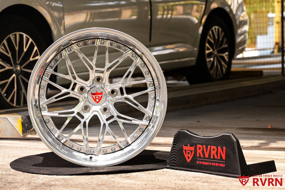 1970 Chevy Nova RV-T081 2-piece forged Y-Spoke Deep Dish wheel with Polished Spoke, Polished Flange, Polished Barrel, and RVRN Red Screws, photographed straight on with the hub opening, five-lug pattern, angular spoke arrangement, polished rim edge, red center emblem, and RVRN sign in the background.