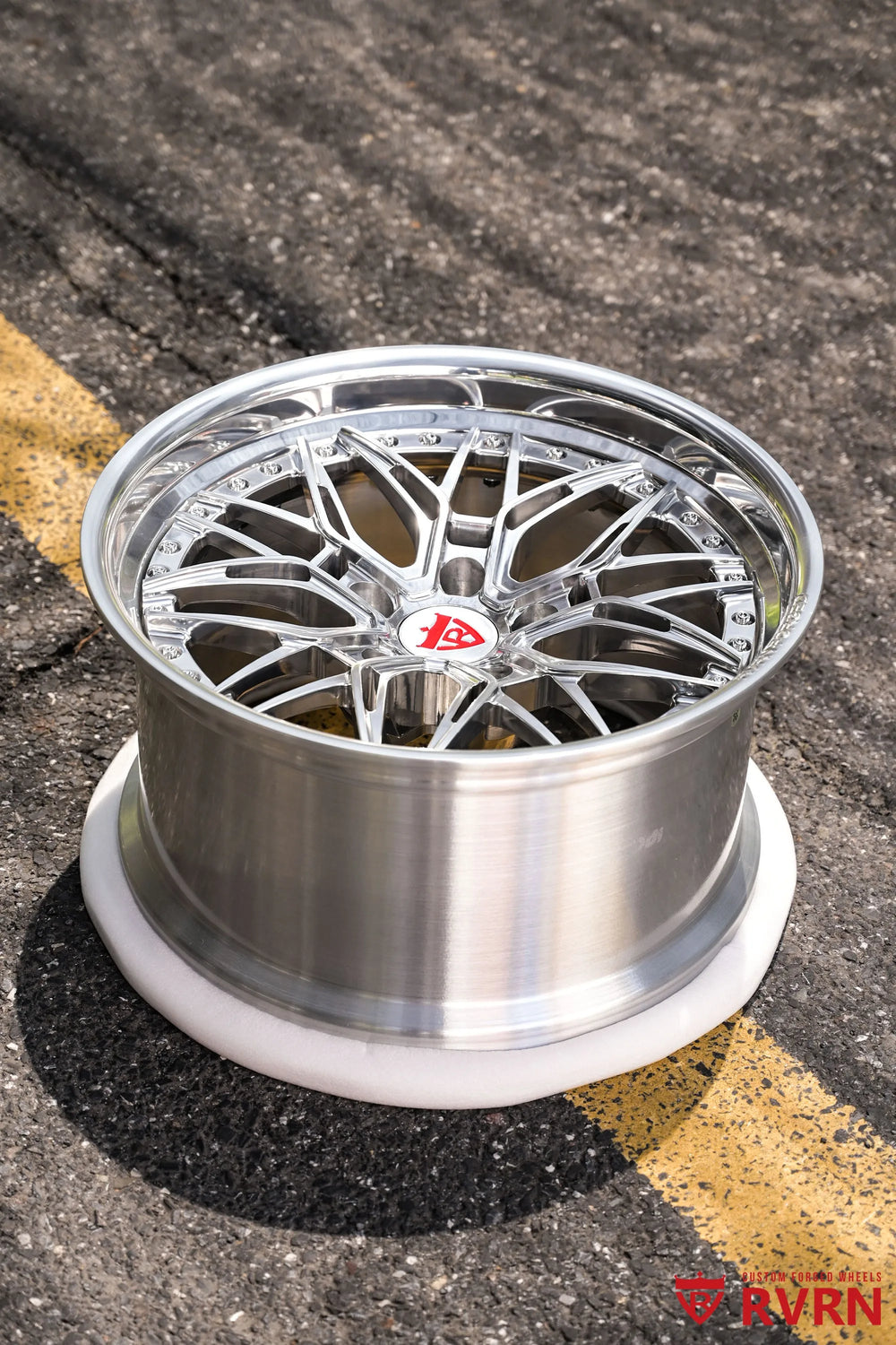 1970 Chevy Nova RV-T081 2-piece forged Y-Spoke Deep Dish wheel with Polished Spoke, Polished Flange, Polished Barrel, and RVRN Red Screws, photographed from a high three-quarter angle on asphalt to show the polished Y-Spoke face, deep outer barrel, red center emblem, flange hardware, and broad dish profile.