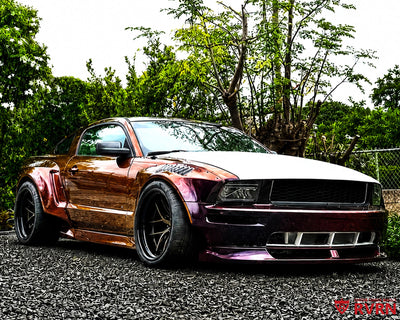 2007 Ford Mustang Widebody on RVRN RV-DR08D super deep dish custom forged wheels in Gloss Bronze Spoke with Gloss Black Barrel, front three-quarter view on gravel showing the iridescent wrap and widebody kit.