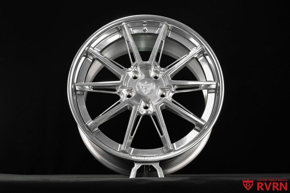 Front-facing studio view of an RVRN RV-DC26 multi-spoke forged wheel for a 2009 Corvette C6 Base, showing the symmetrical spoke arrangement, polished barrel, center cap, lug holes, and reflective All Polished surface.