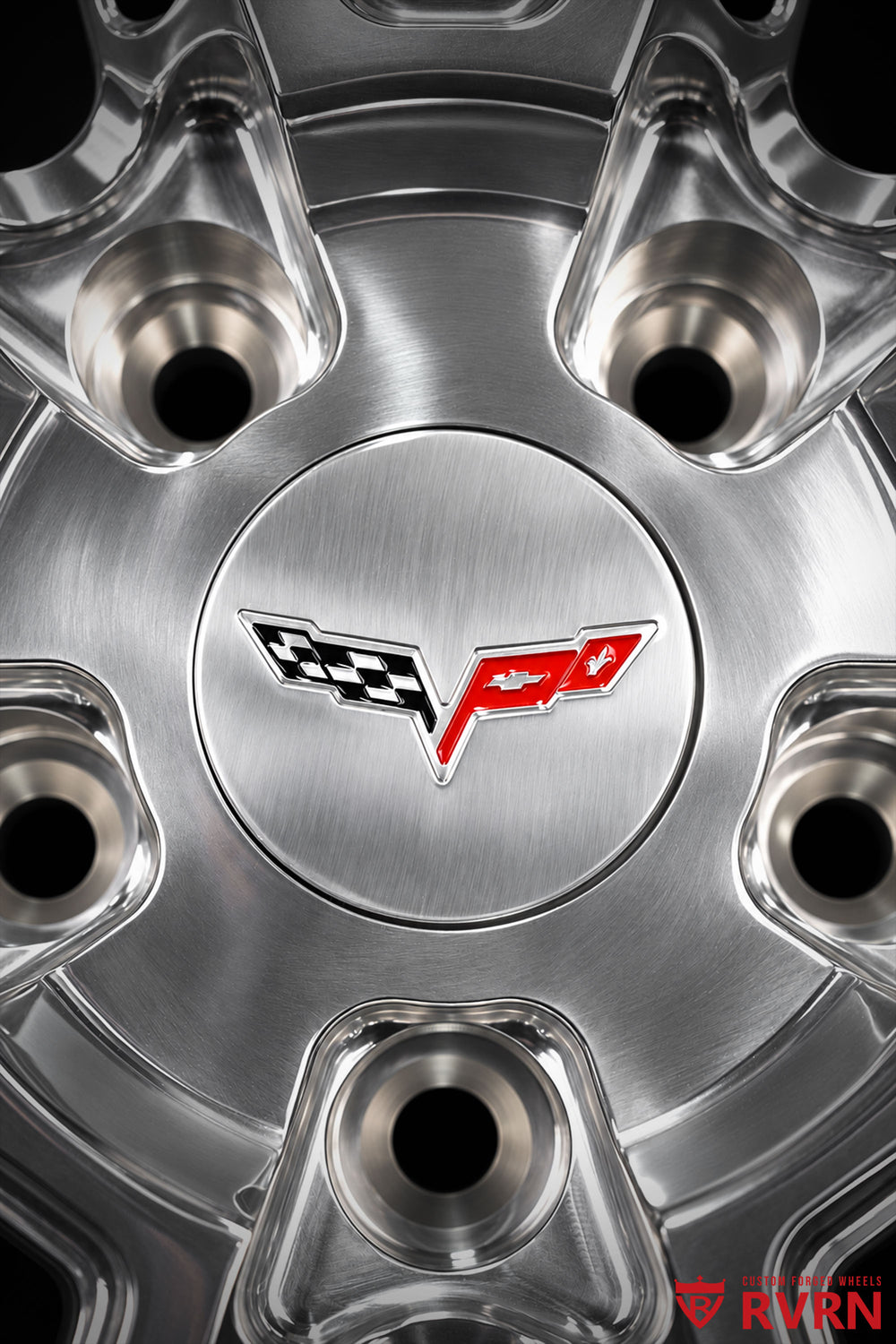 Close-up of the Corvette center logo on an RVRN RV-DC26 multi-spoke forged wheel for a 2009 Corvette C6 Base, surrounded by polished machined metal, lug holes, sculpted spokes, and detailed center construction.