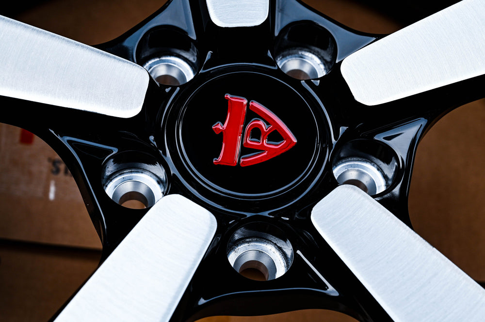 RV-MP223 center hub close-up showing the red RVRN center cap and five lug holes on a gloss black face, built for a 2011 Chevy Camaro LT.