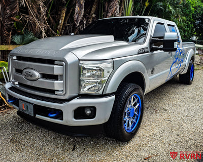2012 Ford F250 Super Duty on RVRN RV-DR08D 2-piece custom forged wheels with Polished Aluminum Spoke and Blue Chrome Barrel, front three-quarter view with custom blue panther graphics.