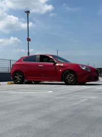 Red Alfa Romeo with bronze custom forged wheels parked on a rooftop, showcasing stylish custom rims under a clear sky.