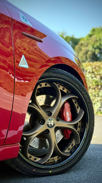 Close-up of Alfa Romeo with custom bronze rims and forged wheels, showcasing unique design and performance.