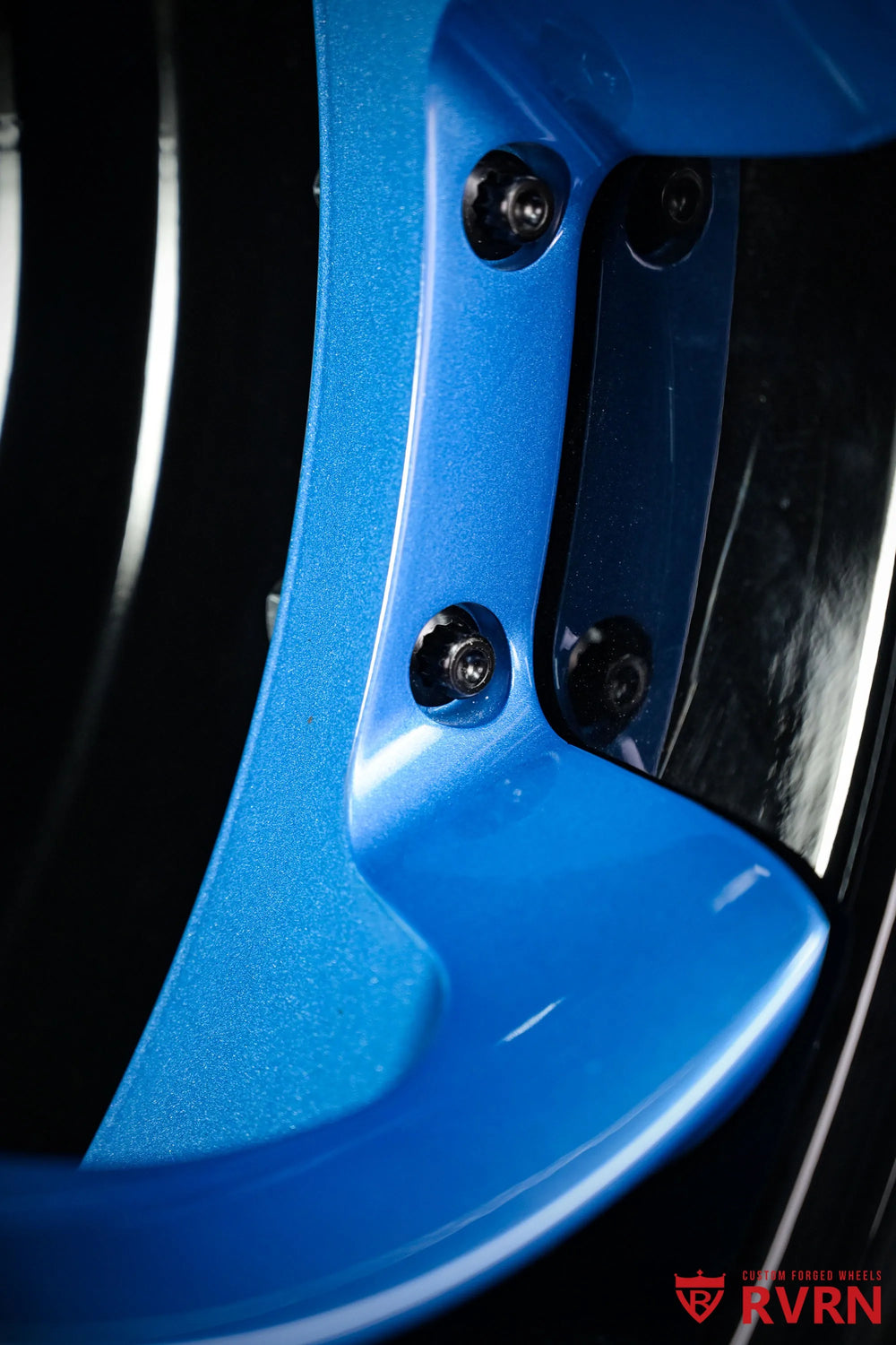 Macro detail of the 2015 Corvette C7 Z51 RV-DS016 forged 2-piece wheel showing blue spoke paint, Gloss Black Barrel., black fasteners, and the reflective inner rim surface