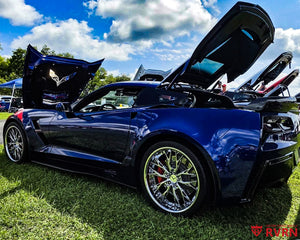 Metallic blue 2017 Corvette C7 Grand Sport on RVRN RV-DC04 chrome custom forged wheels with dark blue screws, displayed at a Corvette car show with hood and hatch open.