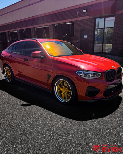 2020 BMW X4M Competition on RVRN RV-DR08D custom forged wheels, side front view at the Goodyear service center showing the deep dish gold design.
