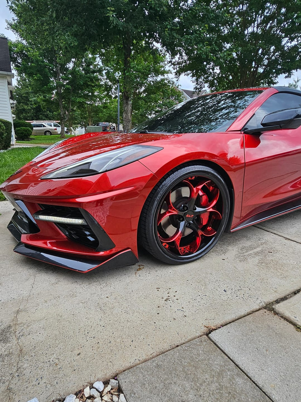 Red Corvette C8 with custom forged black and red wheels on display, showcasing stylish performance and design.