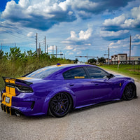 Dodge Charger Widebody with custom forged deep dish rims, featuring purple and black wheels, parked on a gravel road.