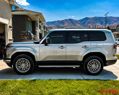 2026 Lexus GX 550 on RVRN RV-MG122 custom forged wheels in Gloss Gunmetal, side profile in front of a suburban home with mountain backdrop.