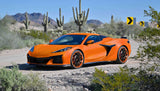 Orange Corvette with custom forged 2-piece wheels driving through desert landscape with cacti and mountains in the background.
