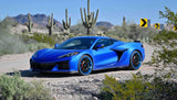Blue Corvette showcasing custom forged 2-piece wheels in a desert backdrop with cacti and directional signs.