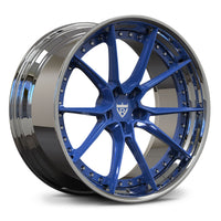 A multi-spoke alloy wheel rim with a polished silver outer lip and a vibrant blue painted inner barrel and spokes, featuring a central shield logo.