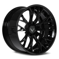 A glossy black multi-spoke aftermarket car wheel rim with a silver Corvette logo on the center cap, shown on a white background.