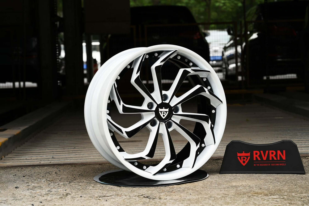 Custom forged Corvette C8 wheels with white and black rims displayed on a stand.