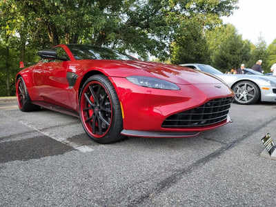 Red Aston Martin V8 Vantage featuring carbon fiber rims and stylish RVRN wheels parked at a car show.