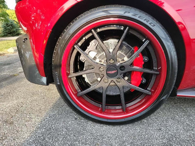 Close-up of Aston Martin V8 Vantage wheels featuring RVRN carbon fiber rims with red accents on a sporty vehicle.