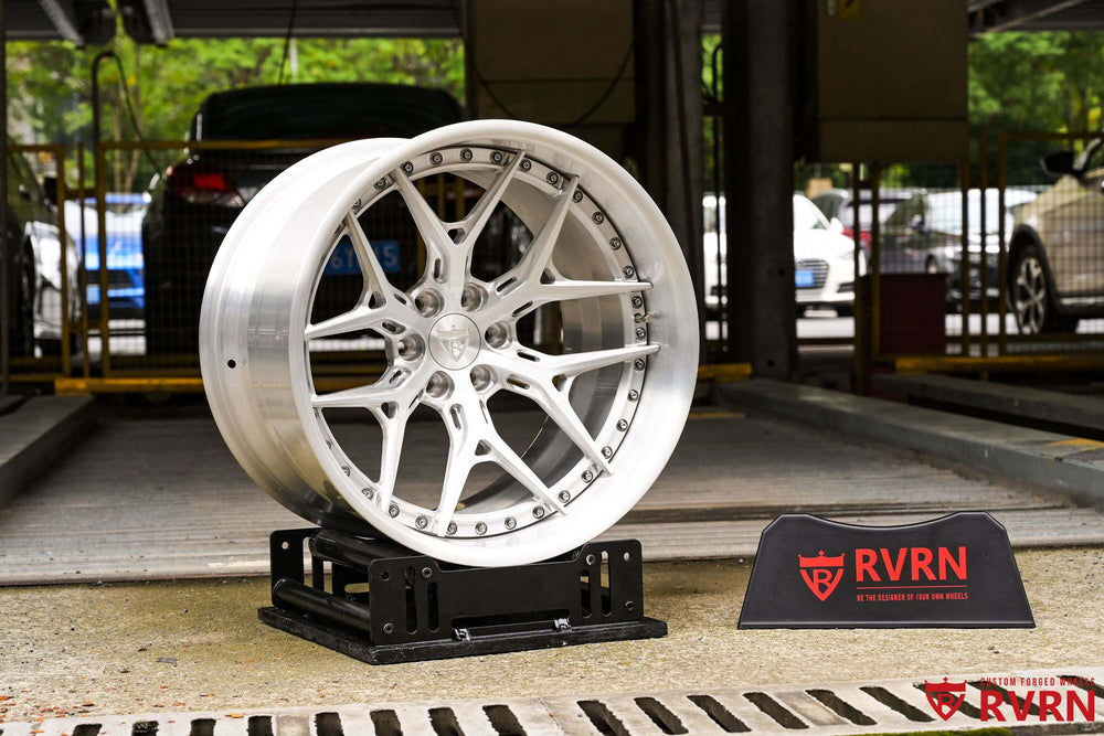 Brushed aluminum RVRN RV-DR08D forged wheel on a display stand beside the RVRN sign in the workshop