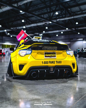 Yellow widebody 2015 Scion FRS rear view with its wing on RVRN RV-DS01 forged wheels, indoor show