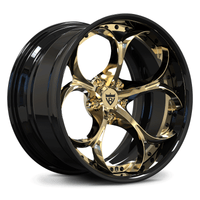 A luxury car wheel rim featuring a glossy black outer barrel and polished gold multi-spoke face, with a central shield logo badge.
