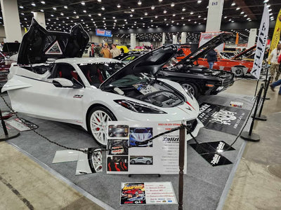 C8 Corvette with white rims showcased at a car show, displaying aftermarket wheels and sleek design.