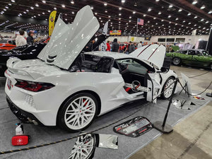 White C8 Corvette showcasing aftermarket wheels, featuring sleek white rims and an eye-catching design at an auto show.