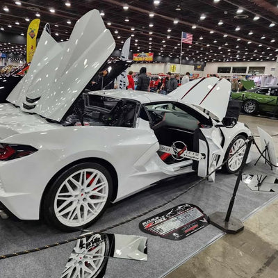 White Corvette C8 showcasing custom aftermarket wheels and rims at a car show, featuring eye-catching design and detailing.