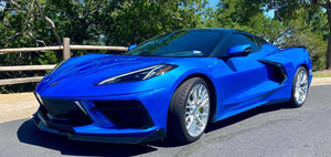 Front three-quarter view of a Riptide Blue 2024 Corvette C8 Stingray on RVRN RV-MC65 brushed aluminum forged wheels by a wooden fence