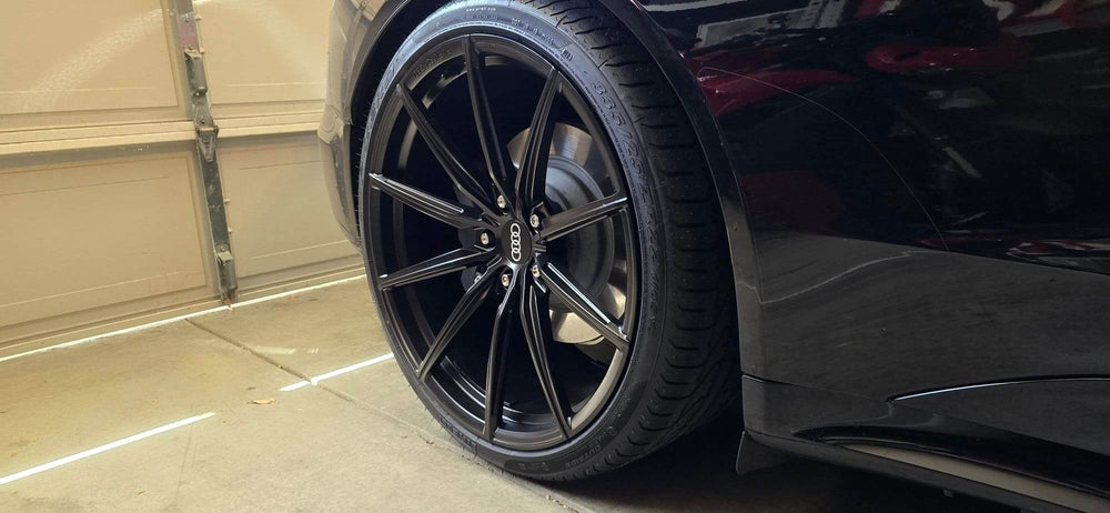 Close-up of Audi RS e-tron GT with black concave rims and 22-inch wheels in garage.