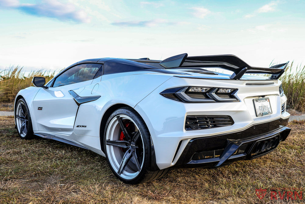Silver Corvette coupe with a rear wing on RVRN forged wheels, rear three-quarter view on the road