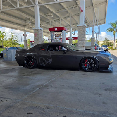 2023 Dodge Challenger Hellcat with custom forged rvrn wheels and staggered 20-inch concave rims at a gas station.