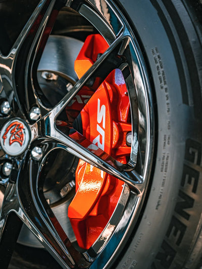 Close-up of 2023 Dodge Challenger Hellcat wheel featuring custom forged 20-inch staggered rvrn rims and red brake calipers.