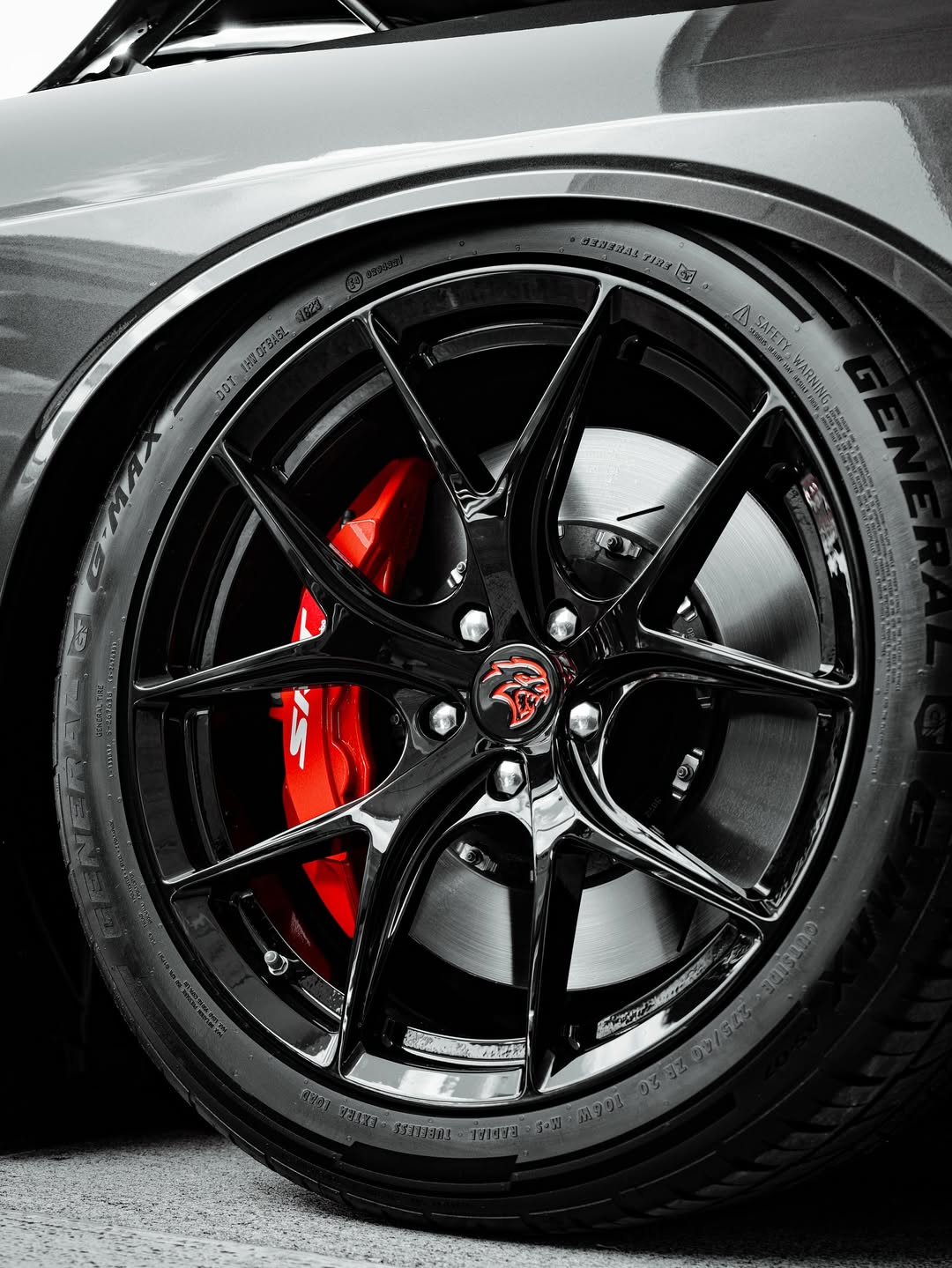 Close-up of 20-inch staggered custom forged wheels on a 2023 Dodge Challenger Hellcat with concave design and red brake calipers.