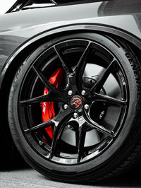 Close-up of 20-inch staggered custom forged wheels on a 2023 Dodge Challenger Hellcat with concave design and red brake calipers.